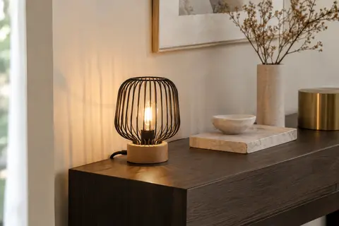 Lampe à poser Jena à structure filaire en métal noir et socle en hêtre, allumée sur une console