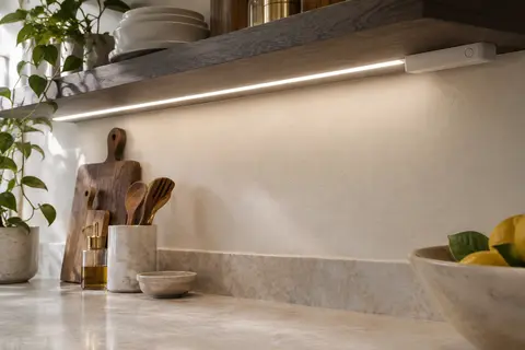 Ruban LED à piles fixé sous une étagère de cuisine, diffusant une lumière blanche neutre sur le plan de travail.