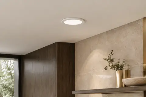 Spot LED rond encastré dans un plafond ivoire, diffusant une lumière douce dans une pièce intérieure.