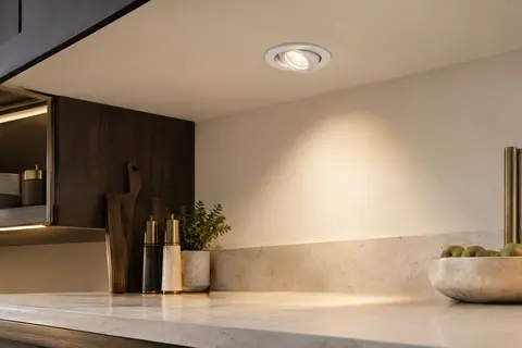 Spot LED encastrable blanc et orientable intégré dans un plafond ivoire au-dessus d’un plan de travail