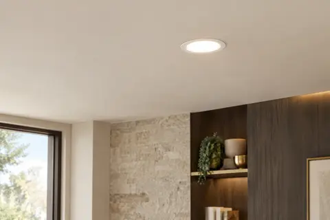 Spot LED encastrable blanc et extra-plat installé dans un plafond ivoire, éclairant doucement une pièce