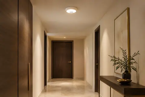 Downlight encastrable blanc avec détecteur PIR intégré, éclairant un couloir intérieur en lumière blanc chaud.