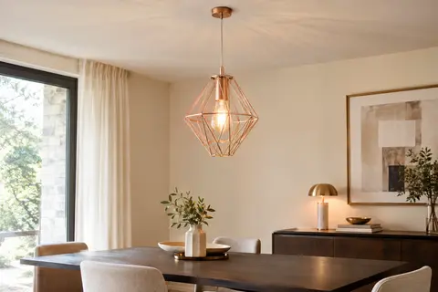 Suspension iDEGU à cage diamant en métal, éclairée au-dessus d’une table en bois dans un intérieur clair.