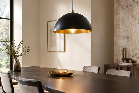 Suspension LEDSone en métal, dôme noir à intérieur doré, installée au-dessus d’une table en bois