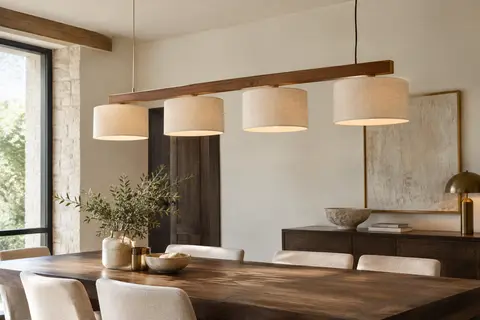 Suspension en bois et tissu beige installée au-dessus d’une table dans une salle à manger lumineuse.