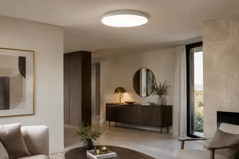 Plafonnier LED rond blanc et mince, allumé au plafond dans un intérieur aux murs ivoire