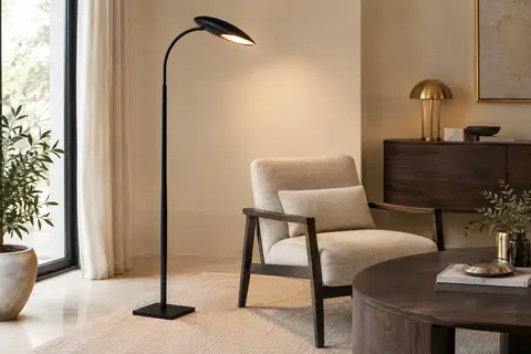 Lampadaire LED noir à tête incurvée et col flexible, installé près d’un fauteuil dans un salon