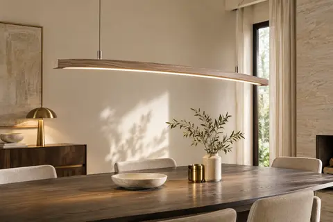 Suspension LED linéaire en bois naturel installée au-dessus d’une table dans un intérieur calme.